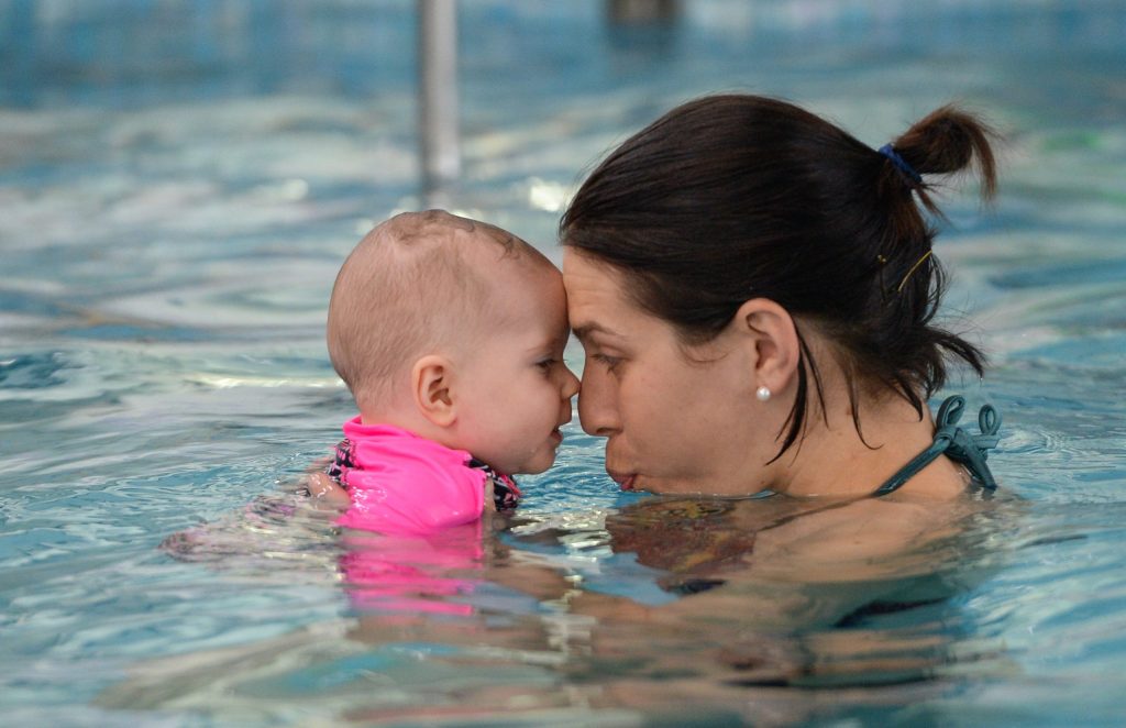 Taking Part In Our Swimming Lessons For Babies Is A Mother & Daughter In The Pool Touching Noses & Looking Each Other In The Eyes